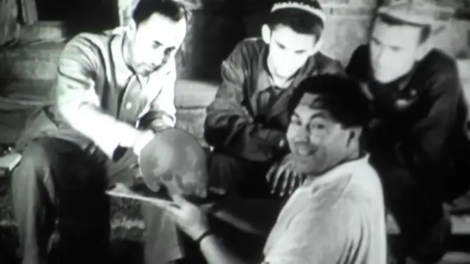 Қабрдан чиқарилган бош чаноғини ушлаб турган антрополог Михаил Гарасимов.