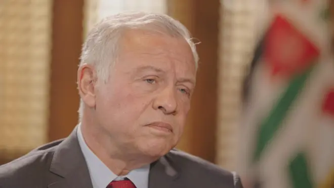 กษัตริย์อับดุลลาห์แห่งจอร์แดนทรงฉลองพระองค์สูทสีเทาและเนคไทสีแดง ทรงมีพระอาการวิตกกังวลขณะทรงนั่งให้สัมภาษณ์กับบีบีซี