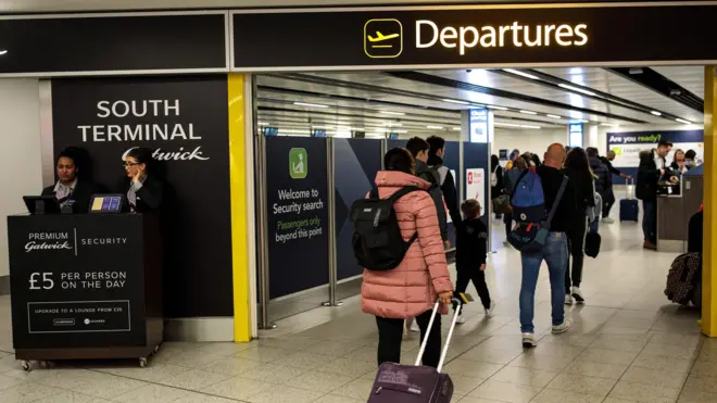 Pasażerowie udają się do bramki odlotów na lotnisku Londyn Gatwick