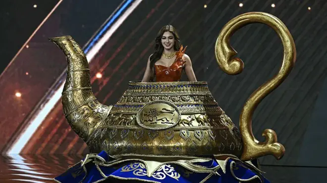 2025 විශ්ව රූ රැජිණ සම්ප්‍රදායික ඇඳුම් තරග වටය අතරතුර ශ්‍රී ලංකා විශ්ව රූ රැජිණ ලිහාෂා වයිට් තේ පෝච්චියක හැඩයට සැකසූ ඇඳුමක් හැඳ වේදිකාවට පිවිසි ආකාරය