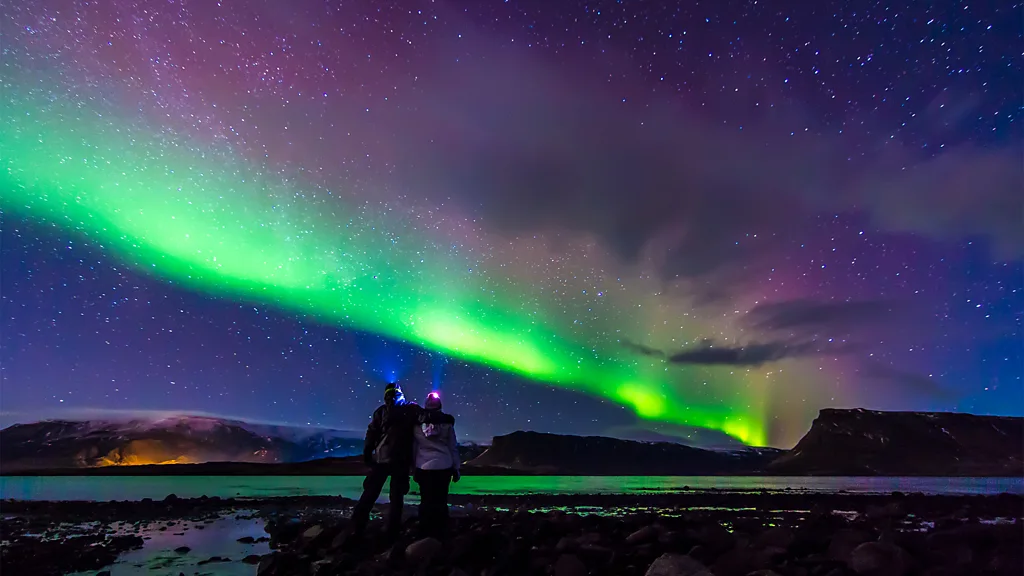 Two people stand viewing the Northern Lights (Credit: Getty Images)