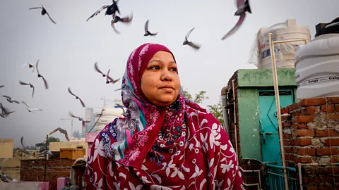 Shaheen Parveen on Delhi rooftop with pigeons flying behind her