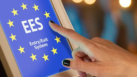 A woman's hand presses a tablet that reads "EES Entry/Exit System" (Credit: Alamy)