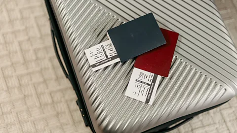 Two passports and boarding passes on top of a silver hard-shell suitcase (Credit: Getty Images)