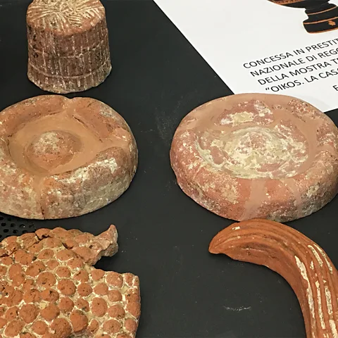 Farrell Monaco Two terracotta flatbreads surrounded by terracotta grapes, carob, pressed ricotta and a pomegranate (Credit: Farrell Monaco)