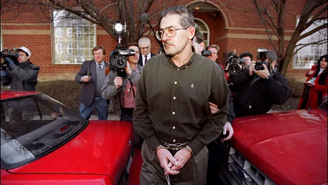 Getty Images Aldrich Ames being arrested in handcuffs, with members of the press taking photos of him from behind (Credit: Getty Images)