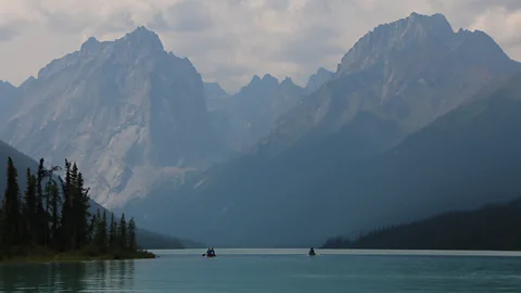 Getty Images A view of the lake with tall mountains in the background in Nahanni National Park Reserve (Credit: Getty Images)