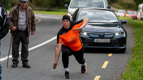 Noel Sweeney Female competitor in orange and black top throwing an iron ball at the Kings and Queens of the Road tournament in Cork (Credit: Noel Sweeney)