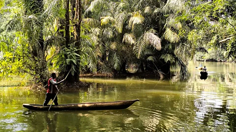 Ali Lucas-Chee Man steering wooden canoe on river to Tiwai Island, Sierra Leone (Credit: Ali Lucas-Chee)