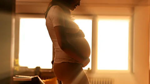Getty Images Pregnant woman standing in front of brightly backlit window (Credit: Getty Images)