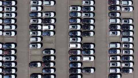 An aerial view of whit and black imported new cars on the quayside of Alexandra Dock at Grimsby Port.