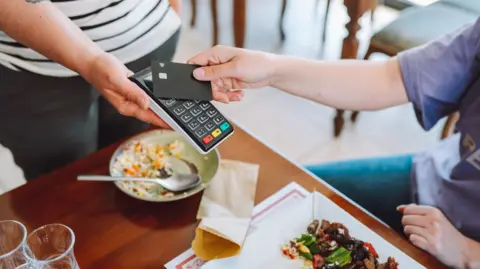 Person paying for food in a restaurant using contactless card 
