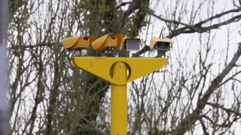 A picture of a yellow speed camera with four different cameras - two facing each way.