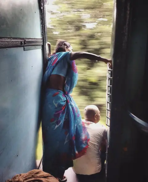 Prince Mandal A woman peers out of a moving train, looking for her stop.