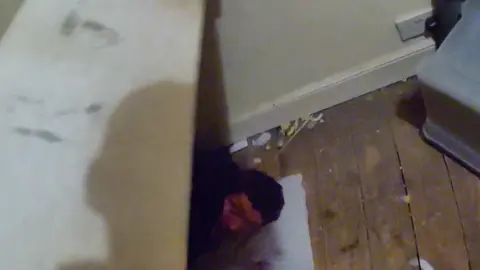 A burglar hiding under a bed is captured by police bodycam