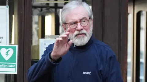 Gerry Adams raises his hand to wave at the High Court in London.