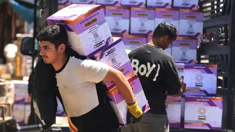 Getty Images Workers unload goods from the back of a truck at the Jamila food market in Sadr City, east Baghdad on April 13, 2026. 